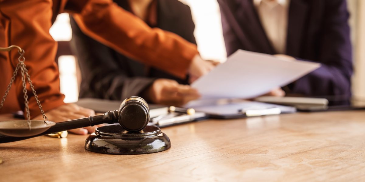 Attorney preparing legal documents in a courtroom with judges and legal professionals in session.