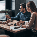 Business professionals analyzing high-ticket lead generation data on a laptop, comparing lead costs across legal, finance, and real estate industries.