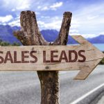 Wooden sign with "Sales Leads" pointing down a scenic road