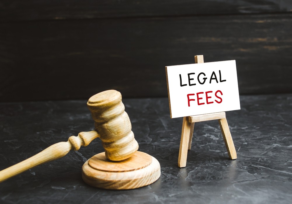 Wooden gavel beside a small easel with a sign reading “Legal Fees”