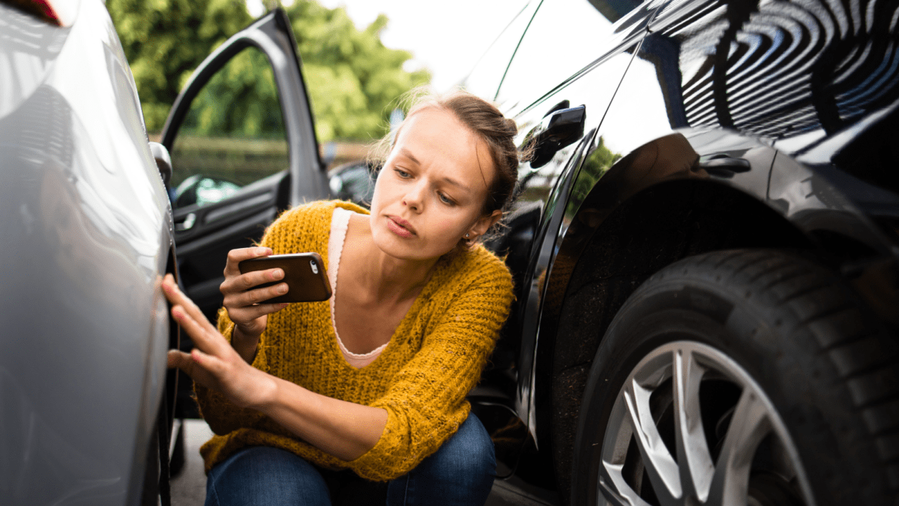 Woman inspecting car dent with phone — how do I get a quote for car damage?