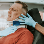 Paramedics placing a neck brace on an injured man after a crash — how do you get whiplash in a car accident