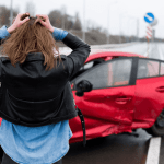 Distressed woman holding her head in shock after car accident showing what a single car accident can lead to in terms of emotional trauma and vehicle damage