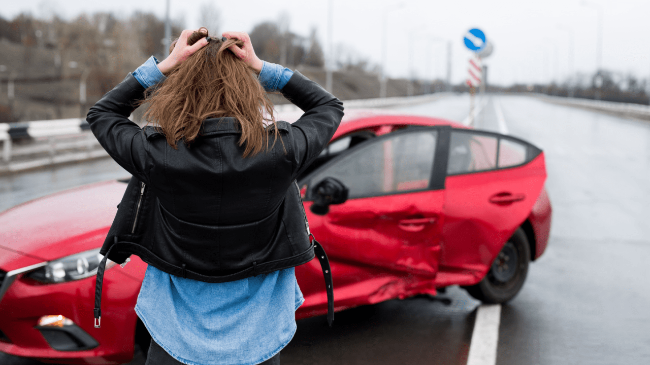 Distressed woman holding her head in shock after car accident showing what a single car accident can lead to in terms of emotional trauma and vehicle damage