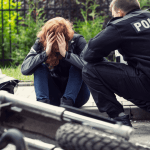 Police officer speaking with distressed woman after motorcycle crash – what is an MVA charge
