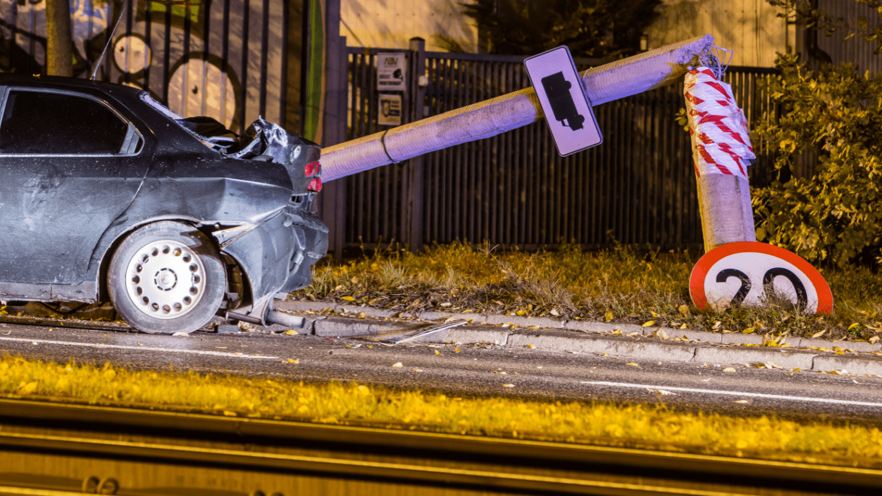 Damaged car at night after crashing into a utility pole – what happens if you hit a pole and leave