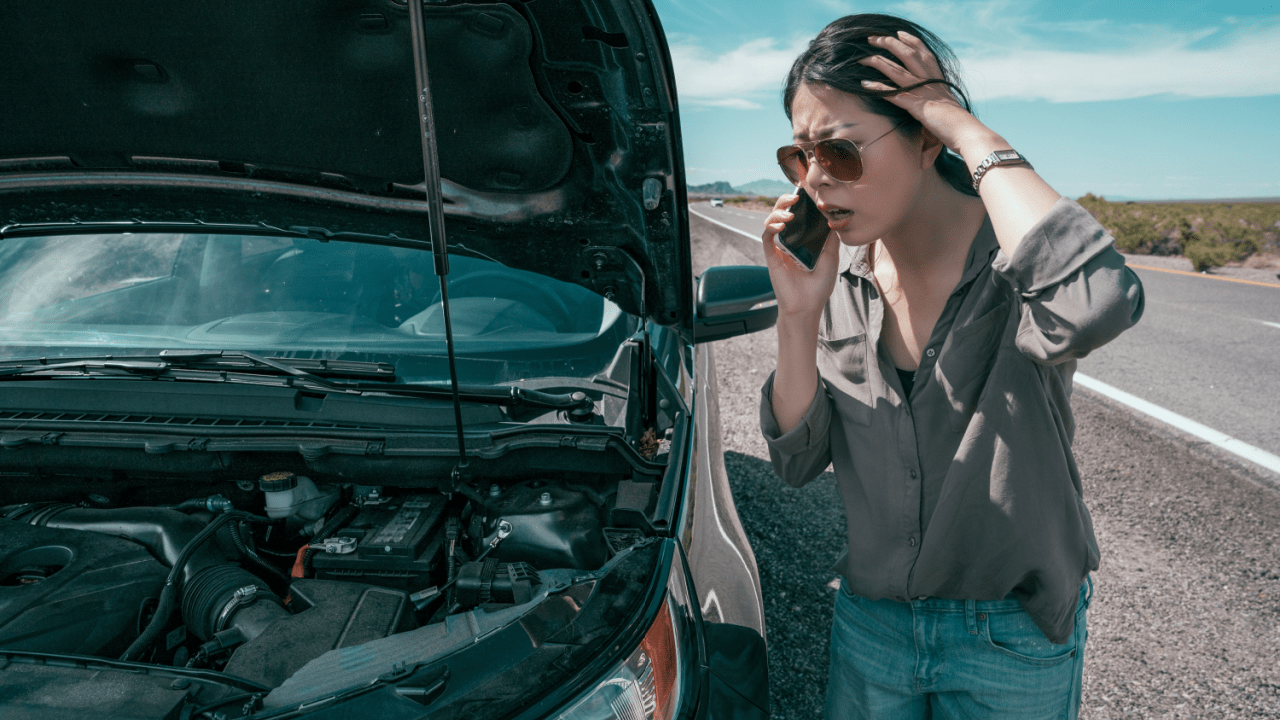 Frustrated woman calling for help beside her broken-down vehicle – what happens when you hit one of your own cars