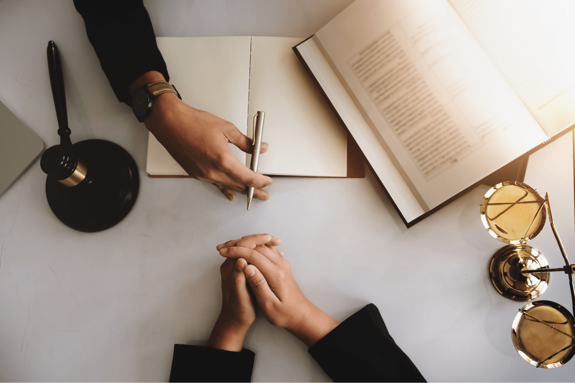 Legal consultation with hands across desk, gavel and law books, discussing what is the new value rule in bankruptcy