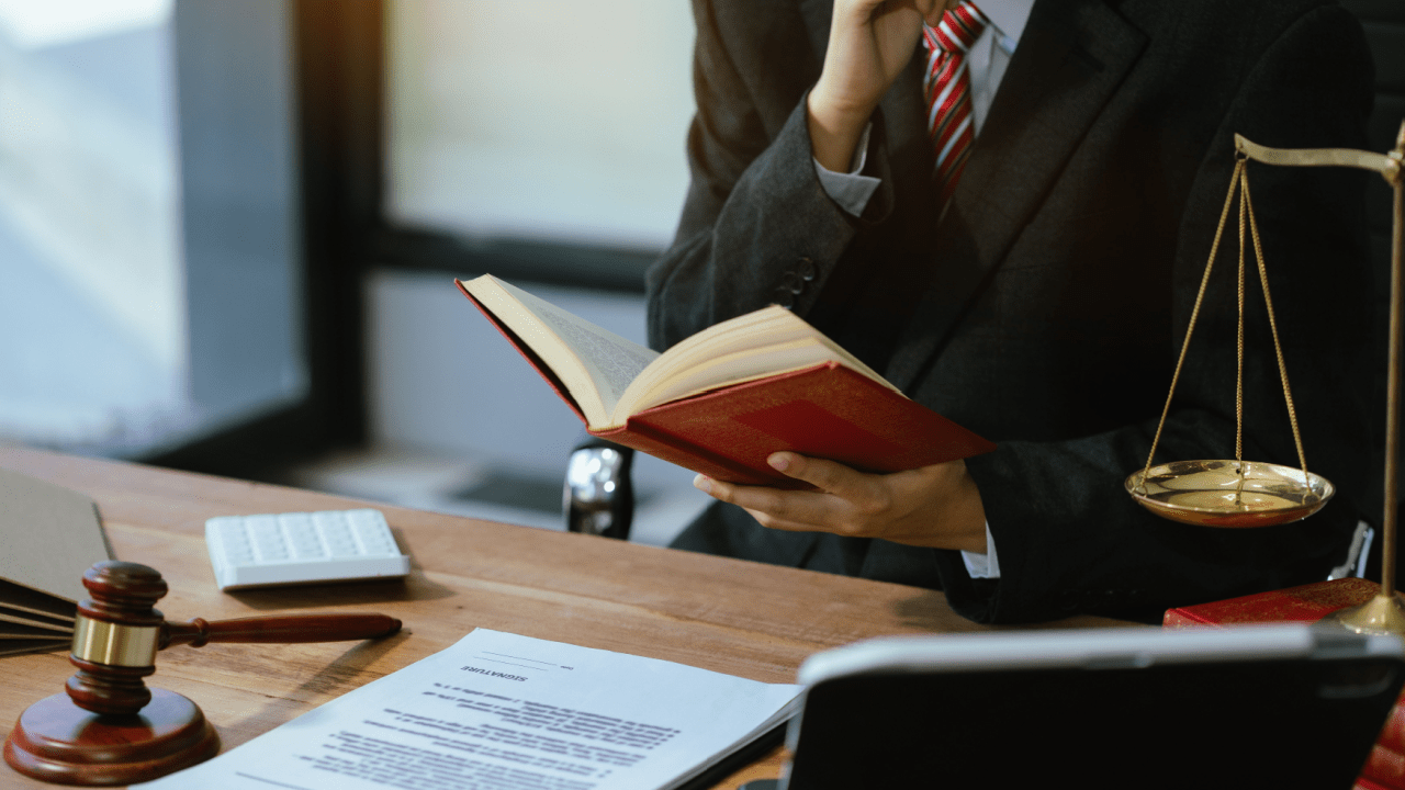 Attorney reading legal book while reviewing court documents and fees, with scales of justice and gavel on desk, researching whether bankruptcy clears court fees