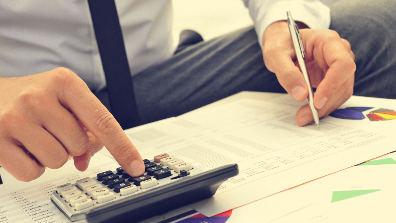 Business professional calculating financial documents with calculator and pen to analyze how do I buy a business in bankruptcy opportunities