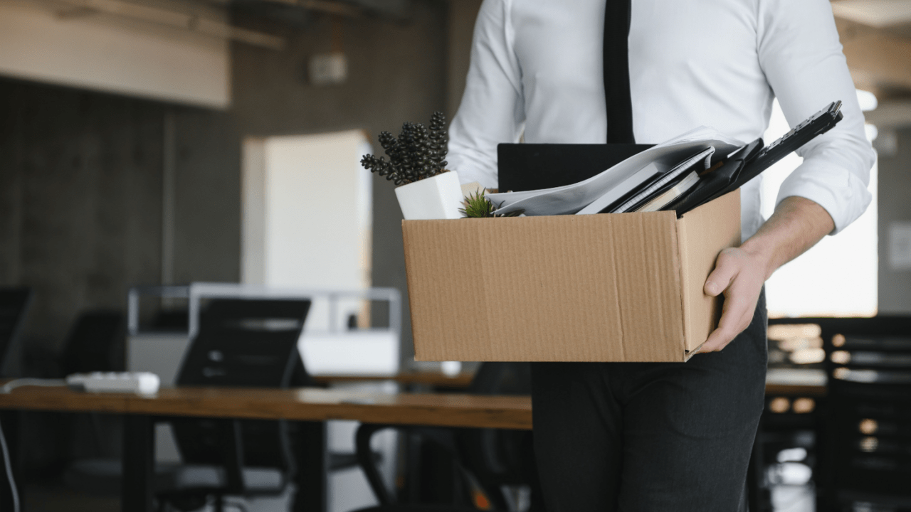 Business professional carrying box of belongings from office, representing the housing search challenge of how do I find a place to live after bankruptcy