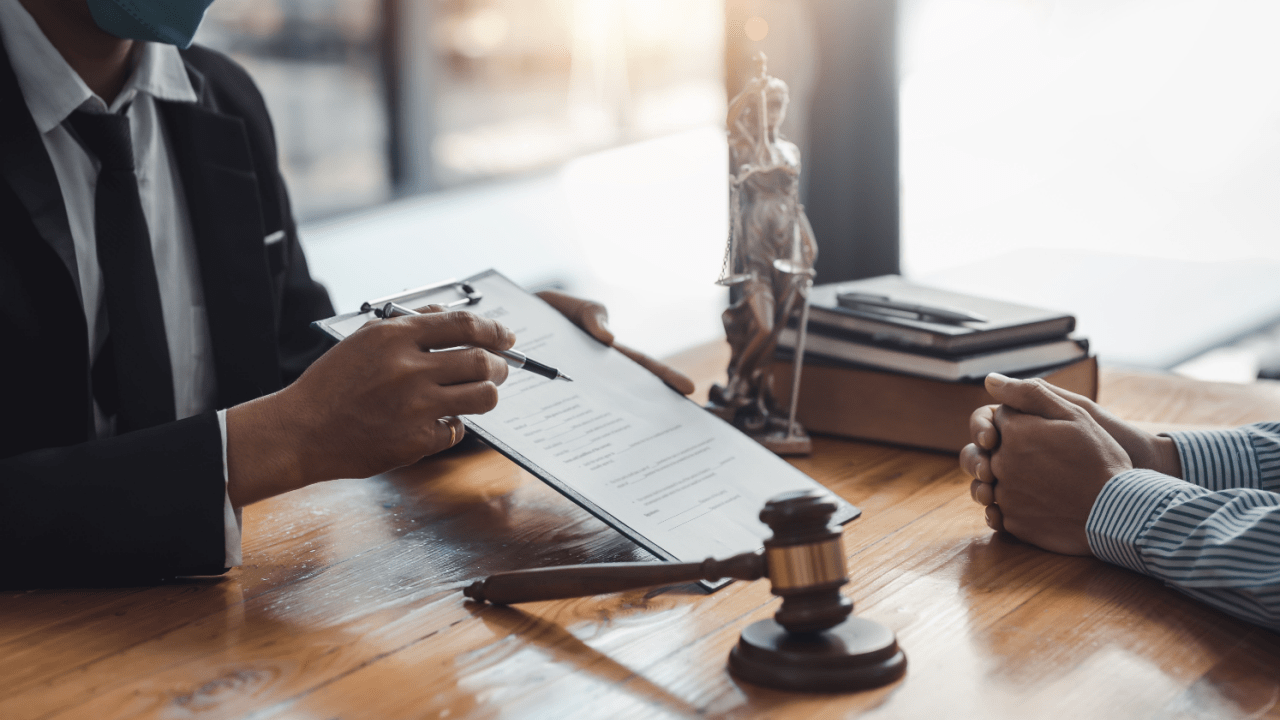 Legal professional reviewing documents with client at desk with gavel and scales, discussing how much does a bankruptcy lead cost for attorney marketing