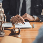 Bankruptcy attorney writing notes at law office desk with Lady Justice statue and gavel, demonstrating whether bankruptcy law is in demand