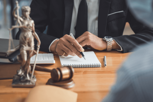 Bankruptcy attorney writing notes at law office desk with Lady Justice statue and gavel, demonstrating whether bankruptcy law is in demand