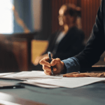 Professional bankruptcy attorney working late at law office desk with documents and brass lamp, illustrating the dedication required to become a bankruptcy attorney