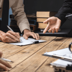 Legal professionals discussing two types of bankruptcies during consultation, with client signing documents and lawyer explaining options at wooden desk