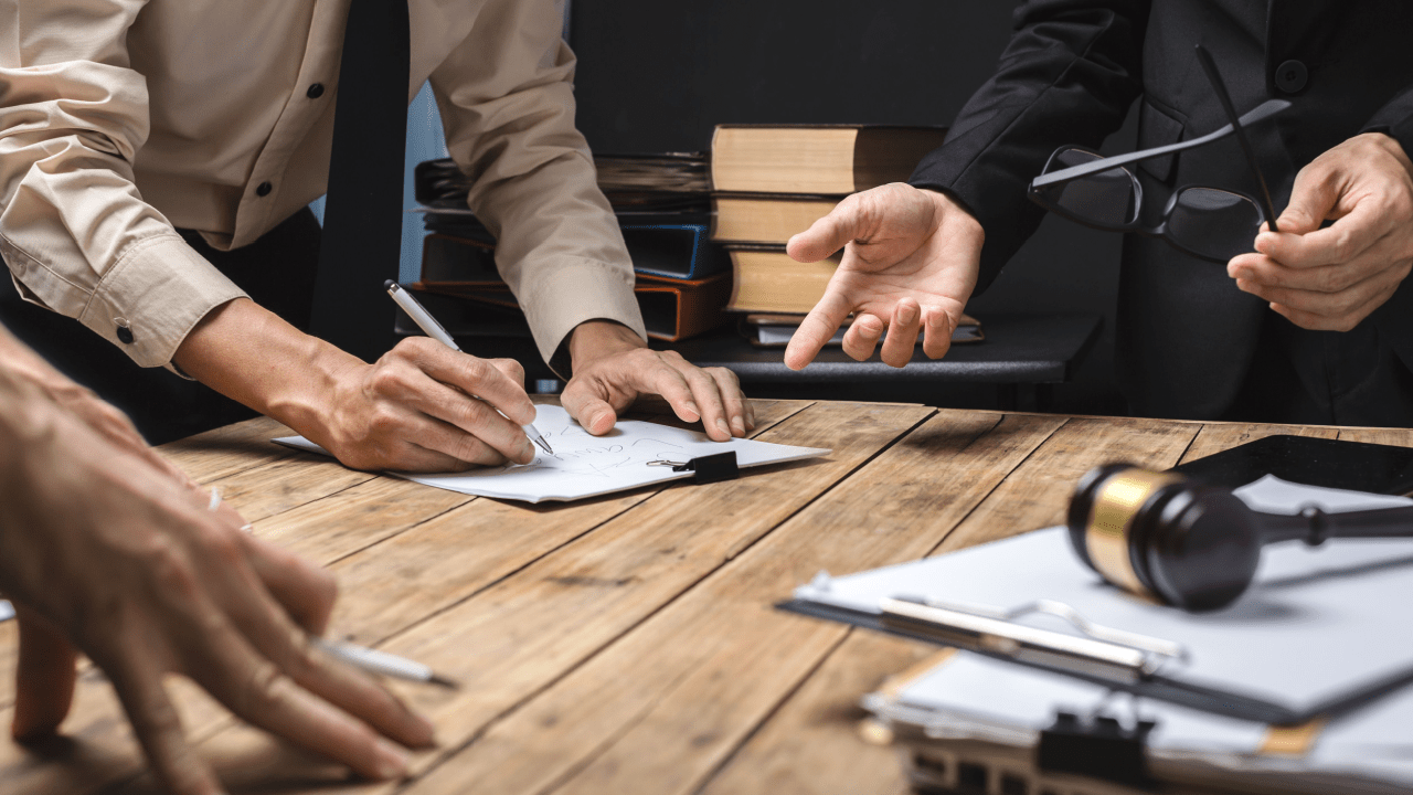 Legal professionals discussing two types of bankruptcies during consultation, with client signing documents and lawyer explaining options at wooden desk