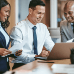 Three legal professionals reviewing client outreach strategies on a laptop — how do I get criminal defense clients?