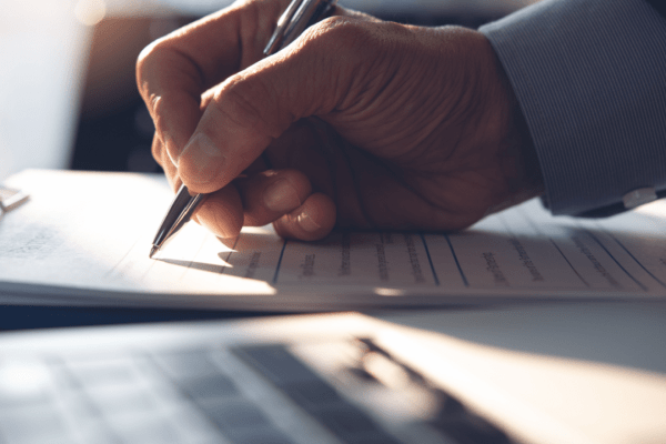 Close-up of a hand signing legal financial paperwork, symbolizing a review of what is the Chapter 5 debt limit.