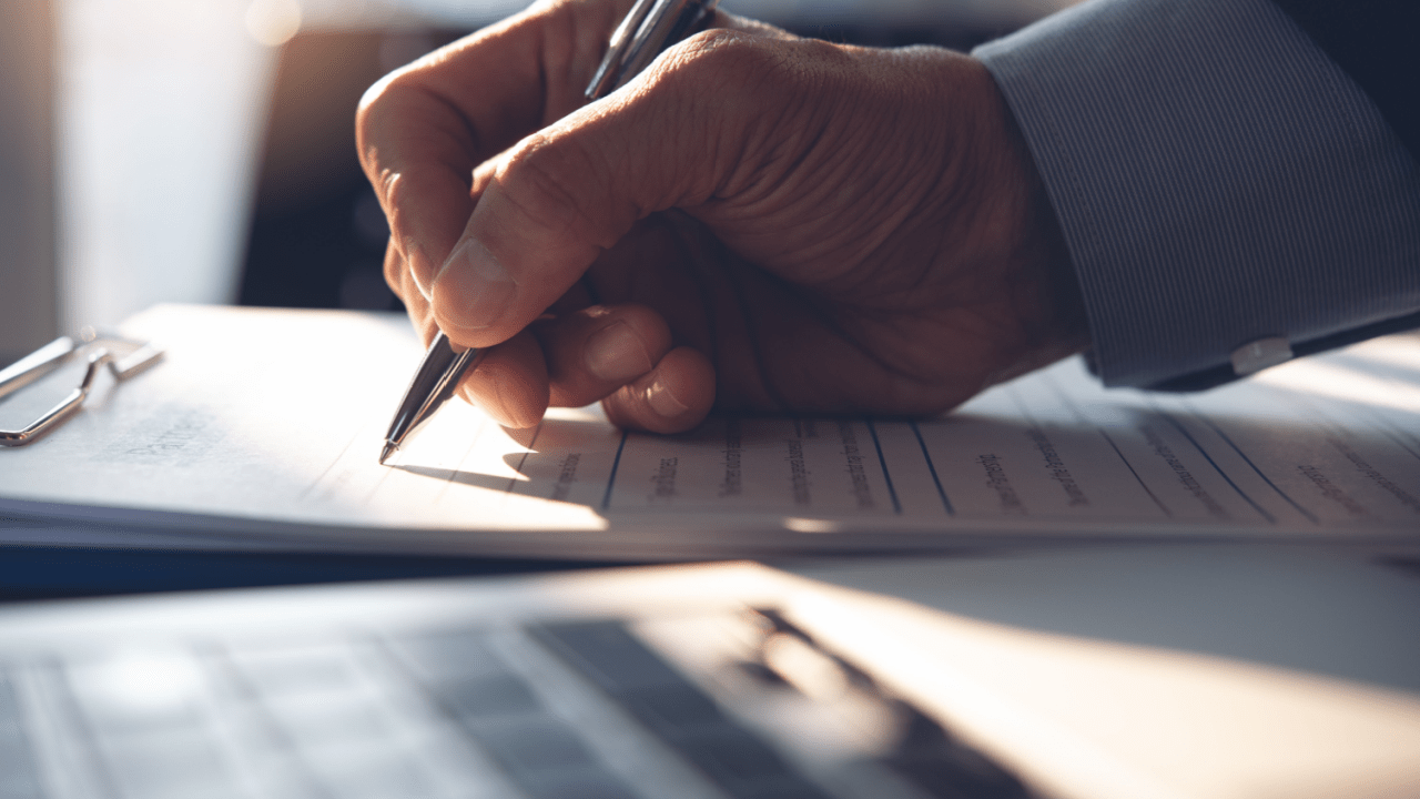 Close-up of a hand signing legal financial paperwork, symbolizing a review of what is the Chapter 5 debt limit.