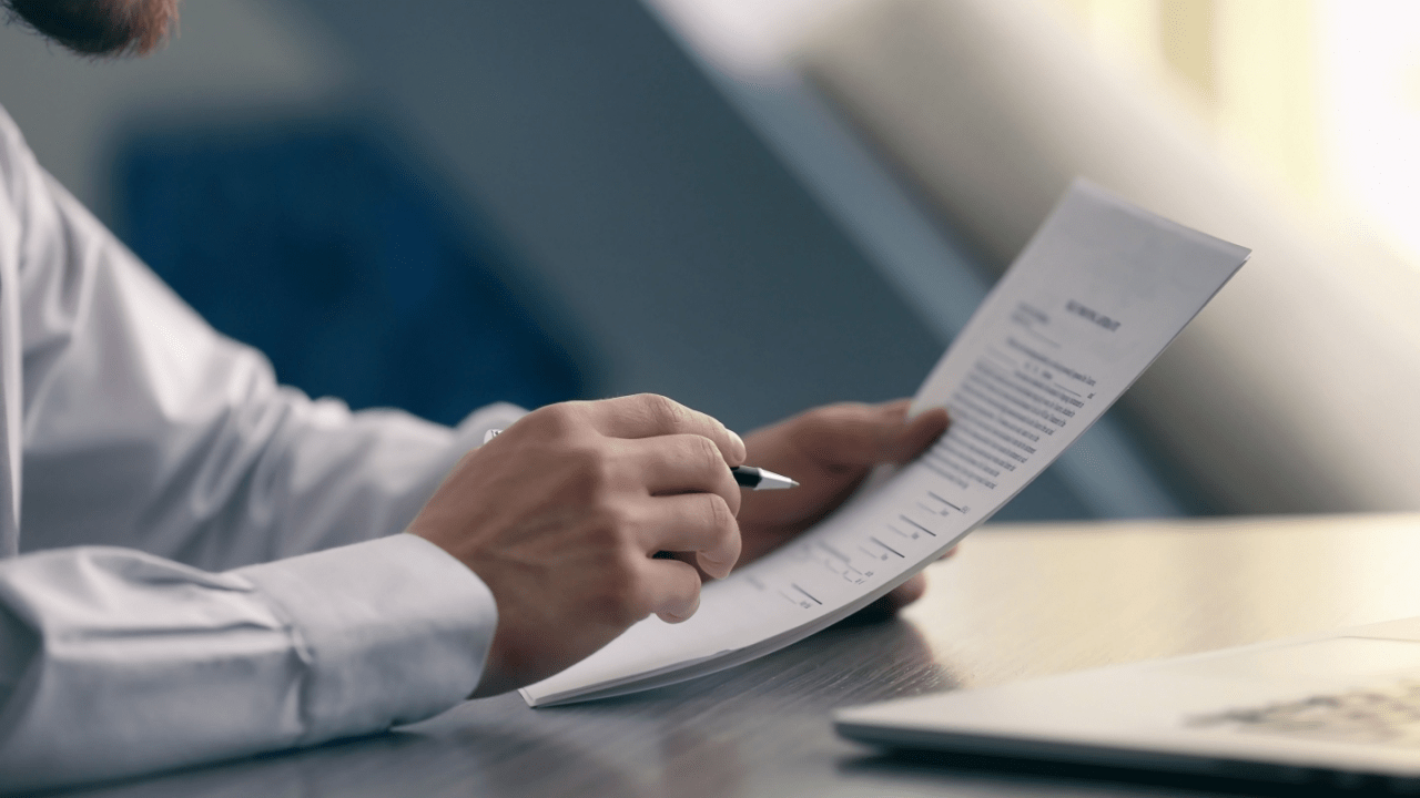 Man reviewing financial documents at a desk, weighing whether is it better to file bankruptcy or just not pay.