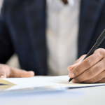 Close-up of a person in business attire signing financial paperwork, questioning if they should file bankruptcy for $10,000 in debt.