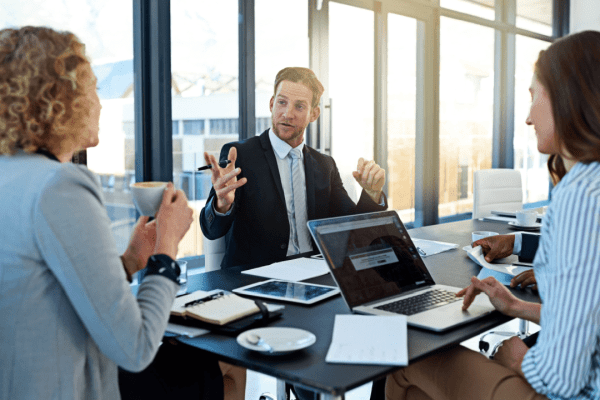 Law firm partners discussing how much does law firm SEO cost during strategy meeting with laptop and documents
