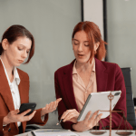 Two attorneys discussing how to create an SEO strategy for a law firm using tablet and smartphone in modern office
