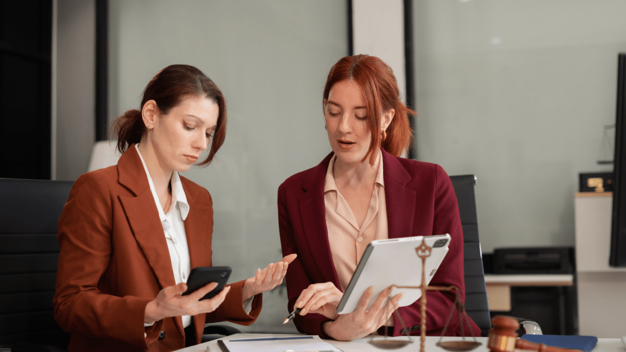 Two attorneys discussing how to create an SEO strategy for a law firm using tablet and smartphone in modern office