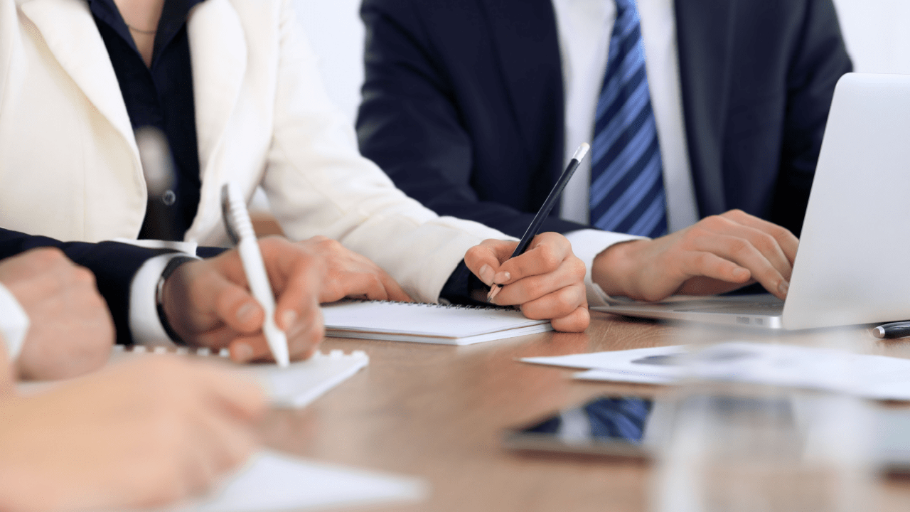 Business professionals discussing is paying someone to do SEO worth it while reviewing proposals and taking notes at meeting