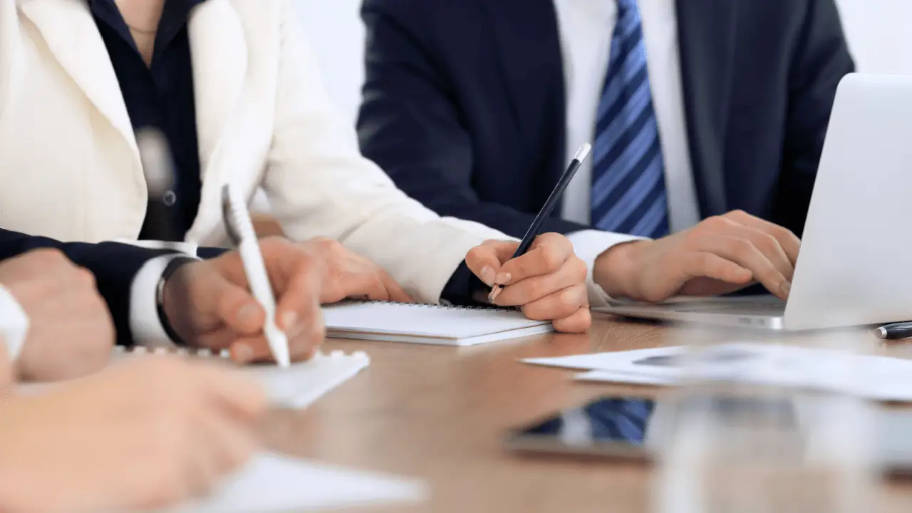 Business professionals discussing is paying someone to do SEO worth it while reviewing proposals and taking notes at meeting