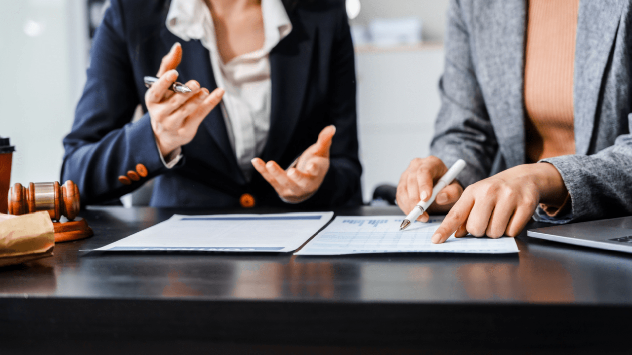Two attorneys discussing what is the role of backlinks in law firm SEO while reviewing analytics and documents with gavel on desk