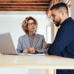 Marketing consultant teaching attorney how to generate bankruptcy leads using laptop in modern office