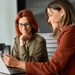 Two professional women discussing how to optimize your law firm for local SEO strategies in a modern office setting