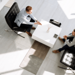 Two business professionals discussing bankruptcy client leads during formal meeting in minimalist office