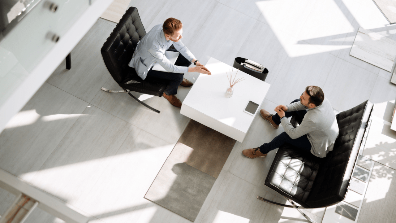 Two business professionals discussing bankruptcy client leads during formal meeting in minimalist office