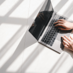 Professional researching options to buy leads for bankruptcy on laptop in bright minimalist workspace