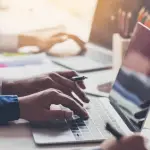 Technical SEO for law firms workspace with professionals typing on laptops surrounded by documents, coffee, and office supplies